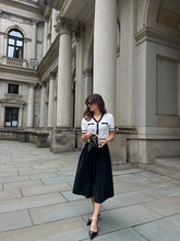a lady in a beige jacquard knit top with a black drop waist midi dress